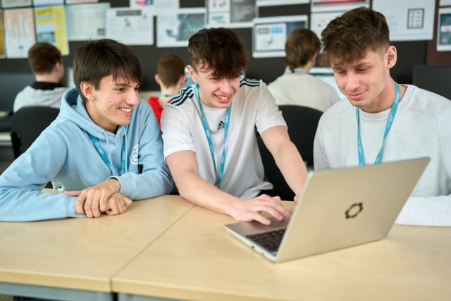 Three Computing T Level students working at a laptop