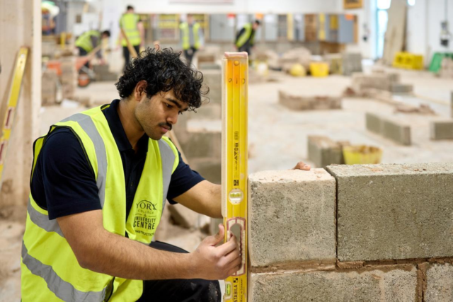 Male bricklayer laying blockwork wall