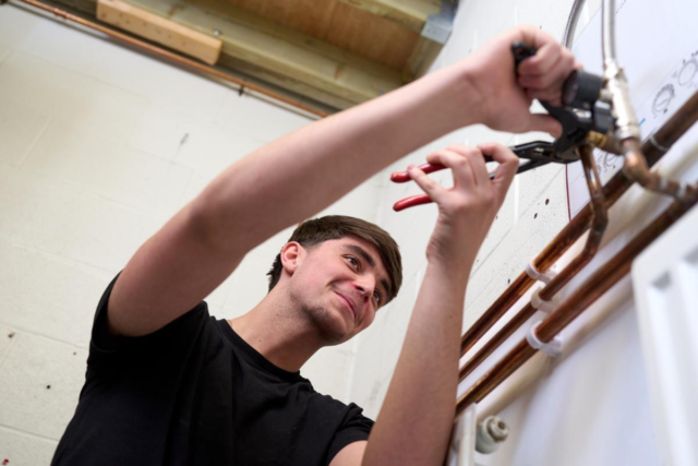 Plumbing student working on pipes