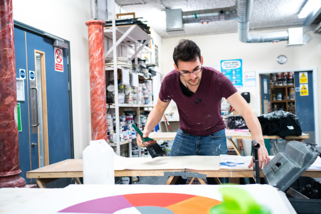 A student puts paste on some wallpaper PD Adult